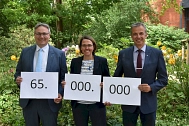 Landrat Marco Prietz, Kreisrat Sven Höhl und Tanja Steinecke mit Zetteln in der Hand, auf denen die Zahl 65.000.000 steht. © Landkreis Rotenburg (Wümme)