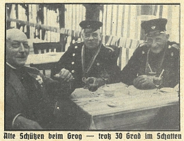 Historisches Bild mit drei Männern an einem Tisch. Zwei der Männer haben eine Schützenuniform an. Auf dem Tisch stehen Getränke. © Landkreis Rotenburg (Wümme)