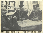 Historisches Bild mit drei Männern an einem Tisch. Zwei der Männer haben eine Schützenuniform an. Auf dem Tisch stehen Getränke.