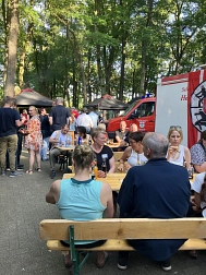 Bierbänke und Tische unter Bäumen. Viele Menschen sitzen und stehen, rechts ist ein rotes Feuerwehrauto zu sehen. © Landkreis Rotenburg (Wümme)