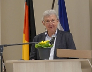 Wolfgang Schiemann steht vor einem Mikrofon an einem Rednerpult. Vor ihm steht eine Blume. © Heinz-Wolfgang Malessa