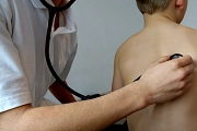 Ein Arzt hört ein Kind mit einem Stethoskop ab.